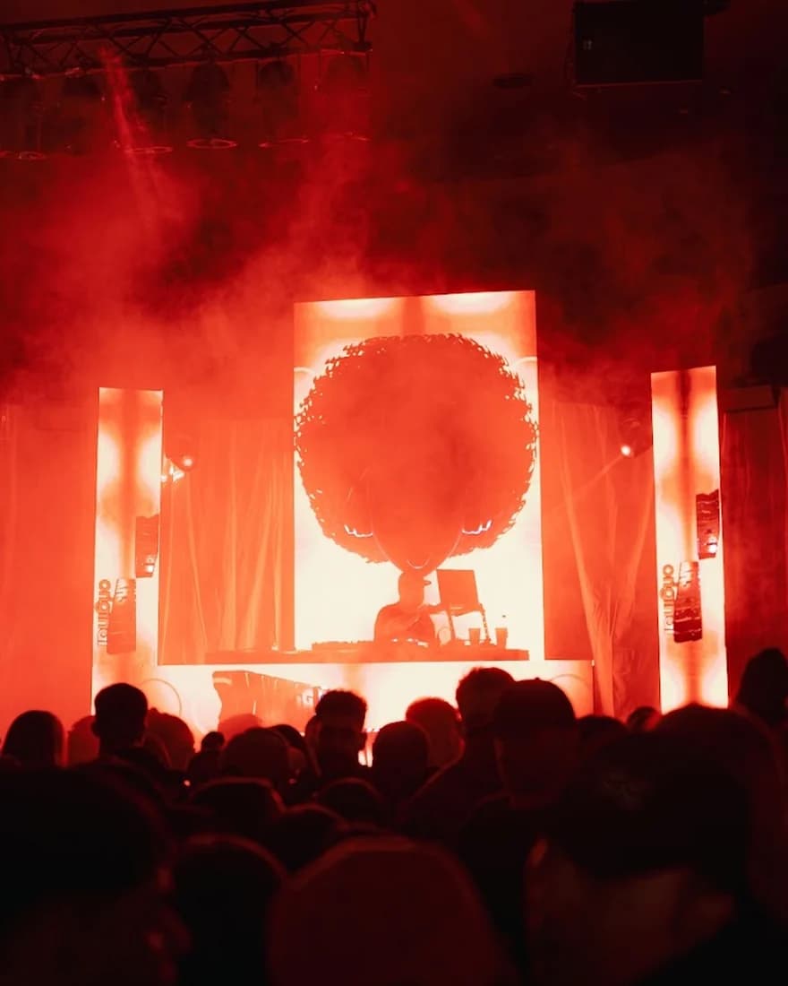 Las pantallas del escenario encendidas en rojo sobre la pista llena
